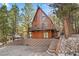 A-frame cabin with a spacious deck, steps, and brick facade nestled in a wooded area at 2160 Via Vita St, Mount Charleston, NV 89124