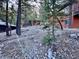 A log cabin exterior with surrounding trees and native, rocky landscaping at 2160 Via Vita St, Mount Charleston, NV 89124