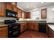 Well-equipped kitchen featuring wooden cabinets, granite countertops, and modern black appliances at 240 Jumping Springs Pl, Henderson, NV 89012