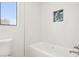Clean bathroom featuring a tub with white tile surround and a decorative accent shelf at 3132 Centavo Dr, Las Vegas, NV 89117