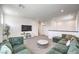 Open living room with a large green corduroy sectional, neutral carpeting, and a television at 3216 Monte Luna Ave, Henderson, NV 89044