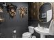 Unique powder room featuring dark walls, gold accents, statement masks, and a pedestal sink at 6848 Calvitero St, Las Vegas, NV 89149