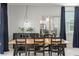 Bright dining room with modern light fixture, wood table and large windows with dark curtains at 6848 Calvitero St, Las Vegas, NV 89149
