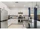 Bright kitchen with white cabinets, stainless steel appliances, black countertops, and a modern island featuring pendant lighting at 6848 Calvitero St, Las Vegas, NV 89149