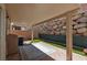 Cozy covered patio area with brick flooring, artificial turf, and a rock wall at 689 Principle Point Ave, Henderson, NV 89012