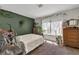 Bright bedroom featuring an olive accent wall, multiple dressers, and decoratively styled window at 7055 Sylvan Oak Dr, Las Vegas, NV 89147
