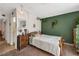 Brightly lit bedroom featuring a cozy bed, green accent wall with decor, and wood dresser at 7055 Sylvan Oak Dr, Las Vegas, NV 89147