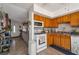Well-lit kitchen with wooden cabinets, white appliances, and tile flooring, seamlessly connecting to the living area at 7055 Sylvan Oak Dr, Las Vegas, NV 89147