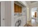 Well-lit laundry room featuring a modern white washer and dryer set, upper cabinets and tile flooring at 7055 Sylvan Oak Dr, Las Vegas, NV 89147