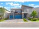 Contemporary two-story home featuring blue garage doors and stone accents at 7307 Grace Estate Ave, Las Vegas, NV 89113