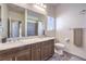 Bathroom featuring double sinks, wood cabinets, and tile floors, as well as a shower with tile surround at 7732 Canon Walk St, Las Vegas, NV 89139