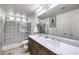 Modern bathroom featuring a dual-sink vanity, a glass-enclosed shower, and neutral tile at 7732 Canon Walk St, Las Vegas, NV 89139