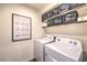 Bright laundry room featuring a white washer and dryer, ample shelf storage, and helpful stain removal guide at 7732 Canon Walk St, Las Vegas, NV 89139