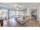 Bright living room with wood floors, a ceiling fan, large grey sectional, and sliding doors to the outside at 7732 Canon Walk St, Las Vegas, NV 89139