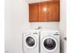Well-lit laundry room with cabinets and modern, front-loading washer and dryer at 7941 Limestone Arch Ave, Las Vegas, NV 89178