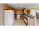 Well-lit kitchen featuring wooden cabinets, tile flooring, and modern white appliances at 10245 Missouri Meadows St, Las Vegas, NV 89183