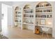 Bright living room features custom built-in bookshelves and desk with white cabinets and a guitar at 10969 Tranquil Waters Ct, Las Vegas, NV 89135