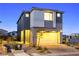 Dusk view of a modern two-story home with gray and white exterior, two-car garage, and desert landscaping at 11800 Black Canary Ave, Las Vegas, NV 89138