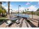 View of a tennis court with seating surrounded by lush palm trees at 2050 W Warm Springs Rd # 2822, Henderson, NV 89014