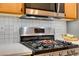 Close-up of a modern kitchen with stainless steel gas range and microwave, complemented by white countertops and tiled backsplash at 2305 W Horizon Ridge Pkwy # 3713, Henderson, NV 89052