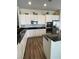 Bright kitchen features white cabinets, black countertops, stainless steel appliances, and wood floors at 2559 Purple Heather Pl, Henderson, NV 89052