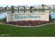 View of the Desert Shores community sign with colorful flowers and lake backdrop and homes at 3151 Soaring Gulls Dr # 1092, Las Vegas, NV 89128