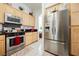 Bright kitchen featuring stainless steel appliances, white tile floor, and light wood cabinets at 3704 Blairmoor St, North Las Vegas, NV 89032