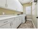 Bright laundry room with a utility sink, white cabinets, and a modern washer and dryer at 3904 Redbreast Ln, North Las Vegas, NV 89084