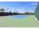 Well-maintained tennis court with vibrant blue and green surface, enclosed by a fence and surrounded by trees at 3904 Redbreast Ln, North Las Vegas, NV 89084
