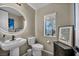 Charming powder room featuring a pedestal sink, framed Nevada art, and a modern, lighted mirror at 460 Pear Lake St, Las Vegas, NV 89138