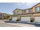 Low angle shot of street lined with townhomes, each featuring a two-car garage at 6247 Milford Sound St, Las Vegas, NV 89148