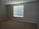 A cozy bedroom featuring a window with blinds and neutral carpet flooring at 7649 Slide Rock Ave, Las Vegas, NV 89113