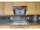 Close up shot of black range hood over gas cooktop and black granite countertop backsplash at 8125 Turbys Treehouse Pl, Las Vegas, NV 89131