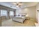 Spacious main bedroom with a ceiling fan, two windows, and neutral walls, complemented by plush carpeting at 8137 Crushed Velvet Pl, Las Vegas, NV 89166