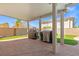 A covered back patio with two BBQ grills and views of the green grass and block wall at 885 Violet Hill St, Las Vegas, NV 89110