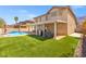 Expansive backyard featuring a pool, covered patio, lush green artificial grass, and privacy at 885 Violet Hill St, Las Vegas, NV 89110