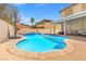 Gorgeous pool with a raised spa, shaded by a red umbrella, with a covered patio and chairs at 885 Violet Hill St, Las Vegas, NV 89110