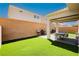 Inviting backyard featuring lush artificial turf, a covered patio with dining set, and a built-in grill perfect for outdoor entertaining at 8929 Sleepy Panda Ave, Las Vegas, NV 89148