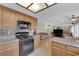 Open concept kitchen boasts granite counters, light wood cabinets, and black appliances at 9021 Feather River Ct, Las Vegas, NV 89117