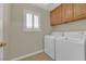 A laundry room featuring a white washer and dryer, a window, and wooden cabinets at 9021 Feather River Ct, Las Vegas, NV 89117