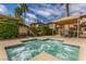 Community hot tub with clear water, seating area, palm trees, and spa regulations sign at 10191 Deerfield Beach Ave # 202, Las Vegas, NV 89129