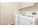 Bright laundry room with white washer and dryer, with tile floor and overhead shelving at 10191 Deerfield Beach Ave # 202, Las Vegas, NV 89129