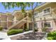 Tan building with manicured hedges and trees, with a stairway leading up to the units at 10553 Pine Pointe Ave # 203, Las Vegas, NV 89144