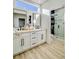 Modern bathroom featuring double sinks, white cabinetry, a large walk-in shower, and plank flooring at 10709 Hunters Woods Pl, Las Vegas, NV 89134