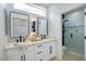 Modern bathroom with double vanity, black hardware, large mirror and glass enclosed shower at 10709 Hunters Woods Pl, Las Vegas, NV 89134
