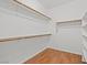 Walk-in closet with wooden floors and multiple storage shelves with white walls creates a tidy and organized space at 10809 Garden Mist Dr # 1004, Las Vegas, NV 89135
