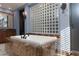 Luxurious bathroom with marble-clad tub beneath a glass block window and elegant fixtures at 2215 Alcova Ridge Dr, Las Vegas, NV 89135