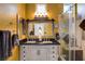 Bathroom featuring a double vanity, framed mirror, and a tiled shower with glass doors at 2305 Hot Oak Ridge St, Las Vegas, NV 89134