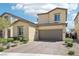 Tan two-story home with two-car garage, brick driveway, and desert landscaping at 2877 Sweeping Palm Rd, North Las Vegas, NV 89086