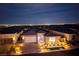 Night shot of a charming home with a brick-accented two-car garage and lush landscaping against a city view at 3000 Dusky Willow Ln, Las Vegas, NV 89138